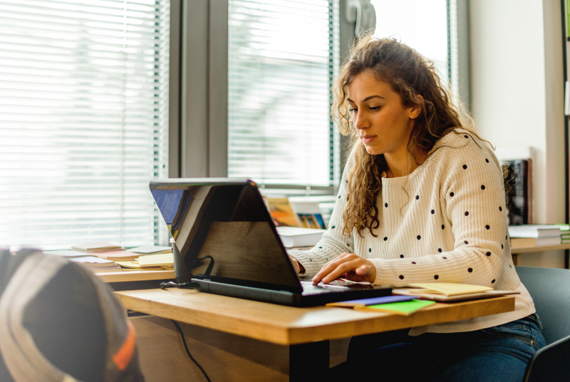 Woman typing on laptop while studying for the GRE.